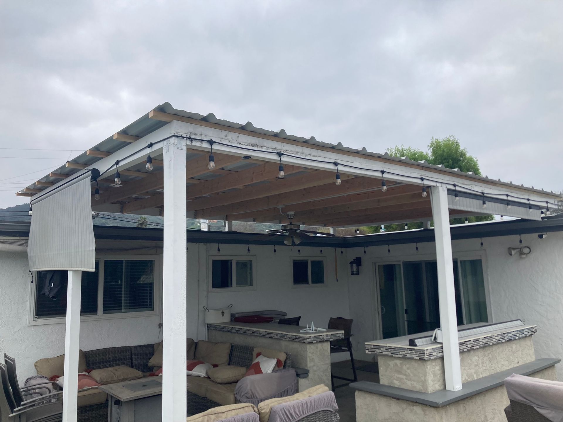 A patio with a pergola and a couch and chairs underneath it.