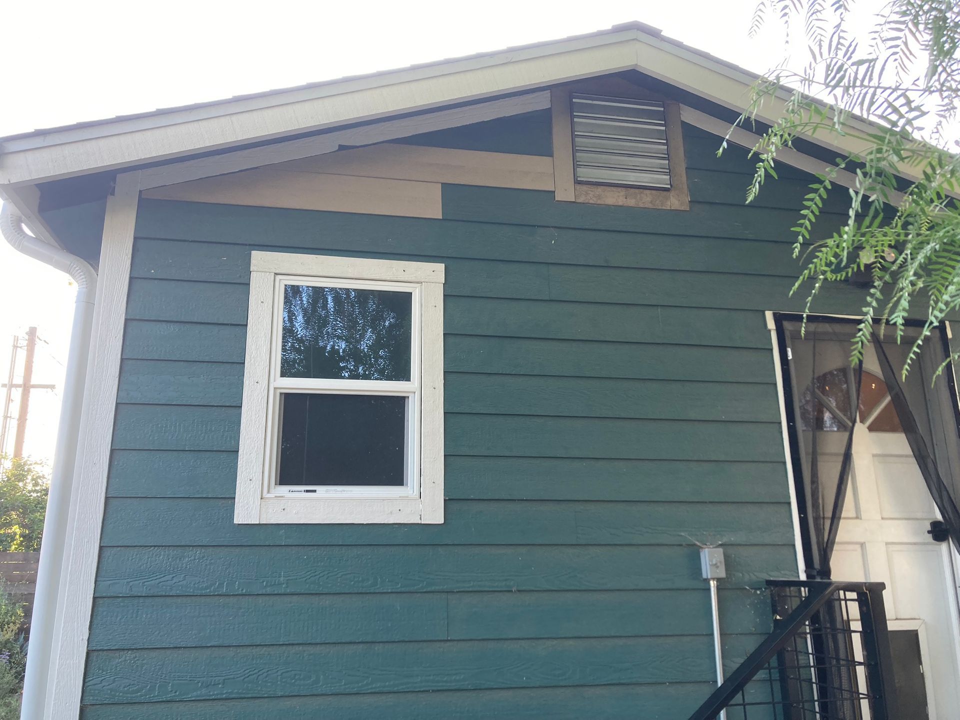 A blue house with a white window on the side