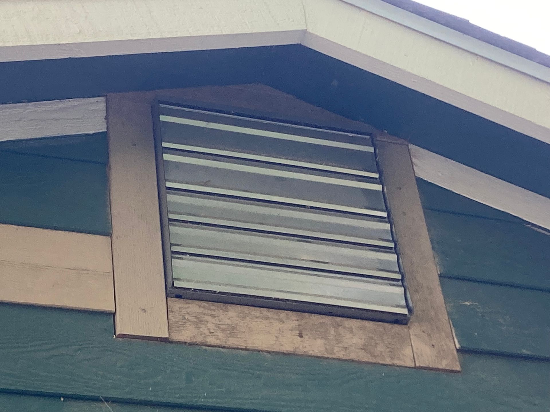 A window on the side of a building with a metal shutter