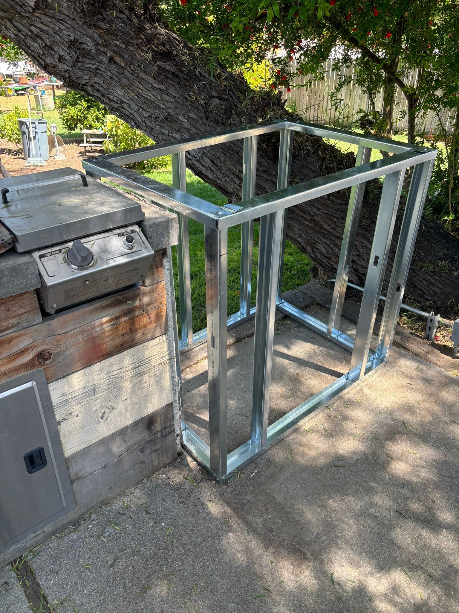 A metal frame is sitting on the ground next to a grill.
