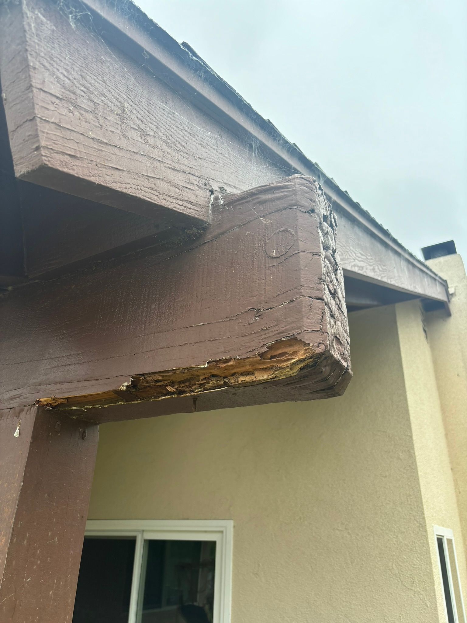 A wooden beam is missing from the roof of a house.
