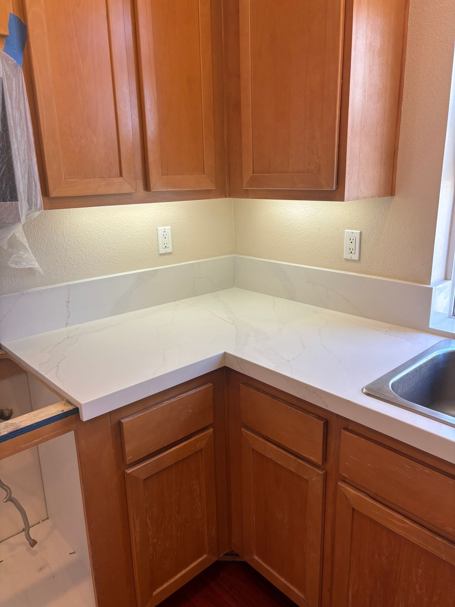 Kitchen with light wooden cabinets and white countertops.