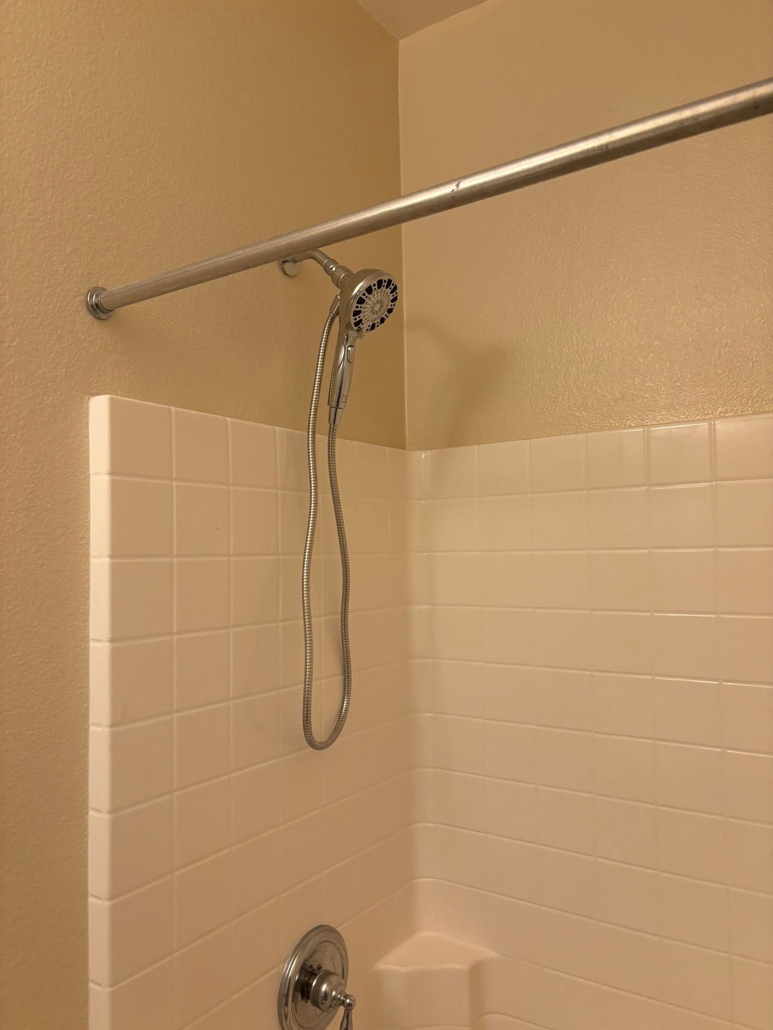 A shower head is hanging from a shower curtain in a bathroom.