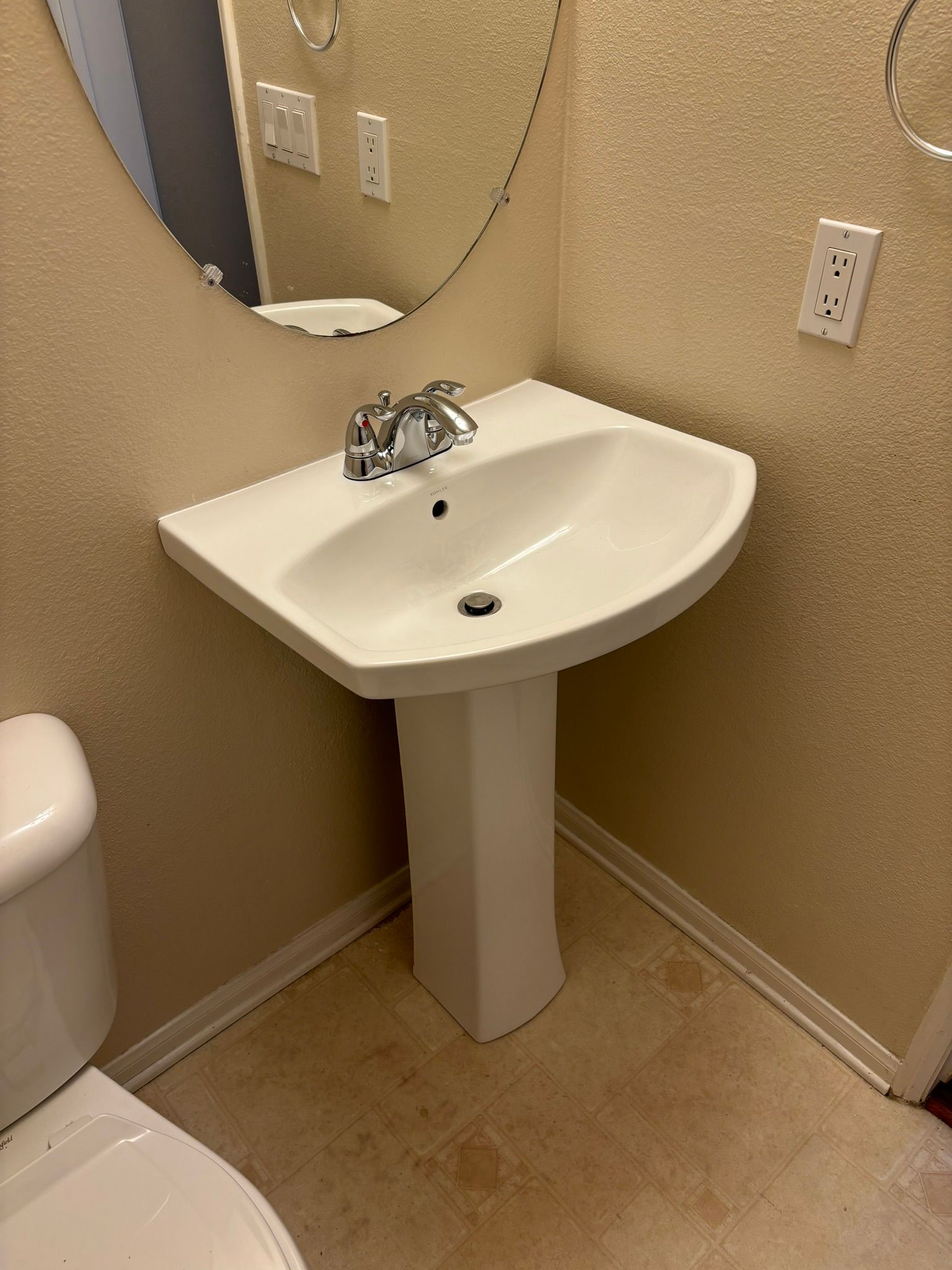 A bathroom with a pedestal sink , toilet and mirror.
