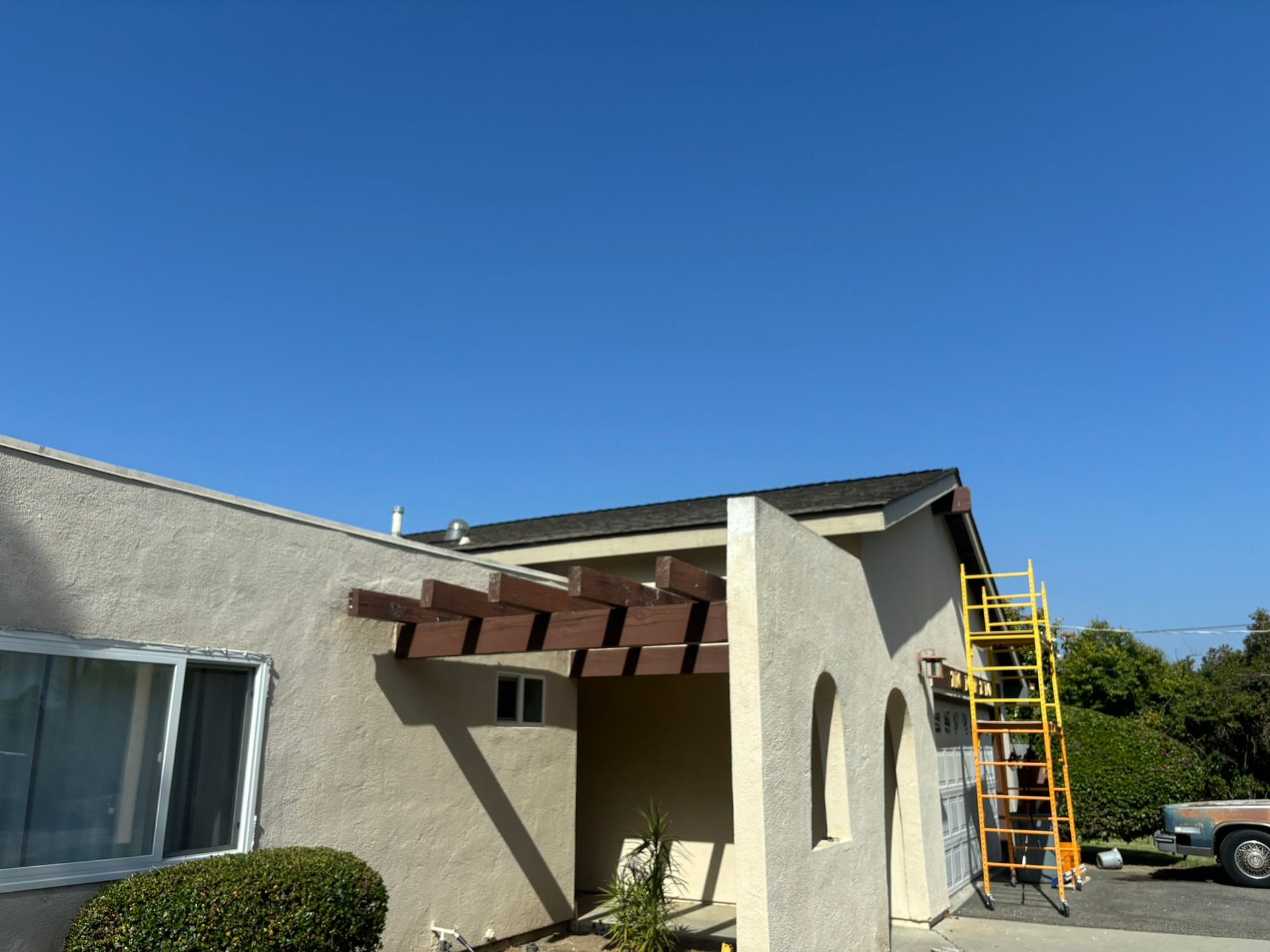 A house with a pergola and a ladder in front of it