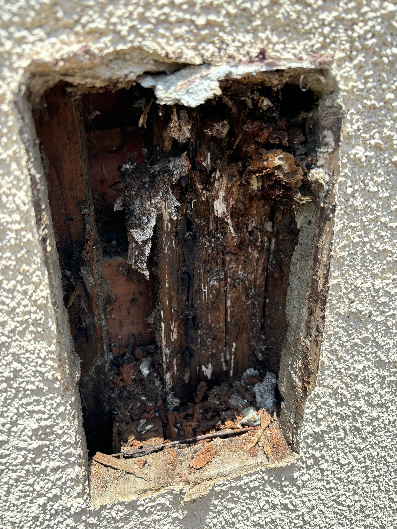 A hole in a wall with a piece of wood sticking out of it.