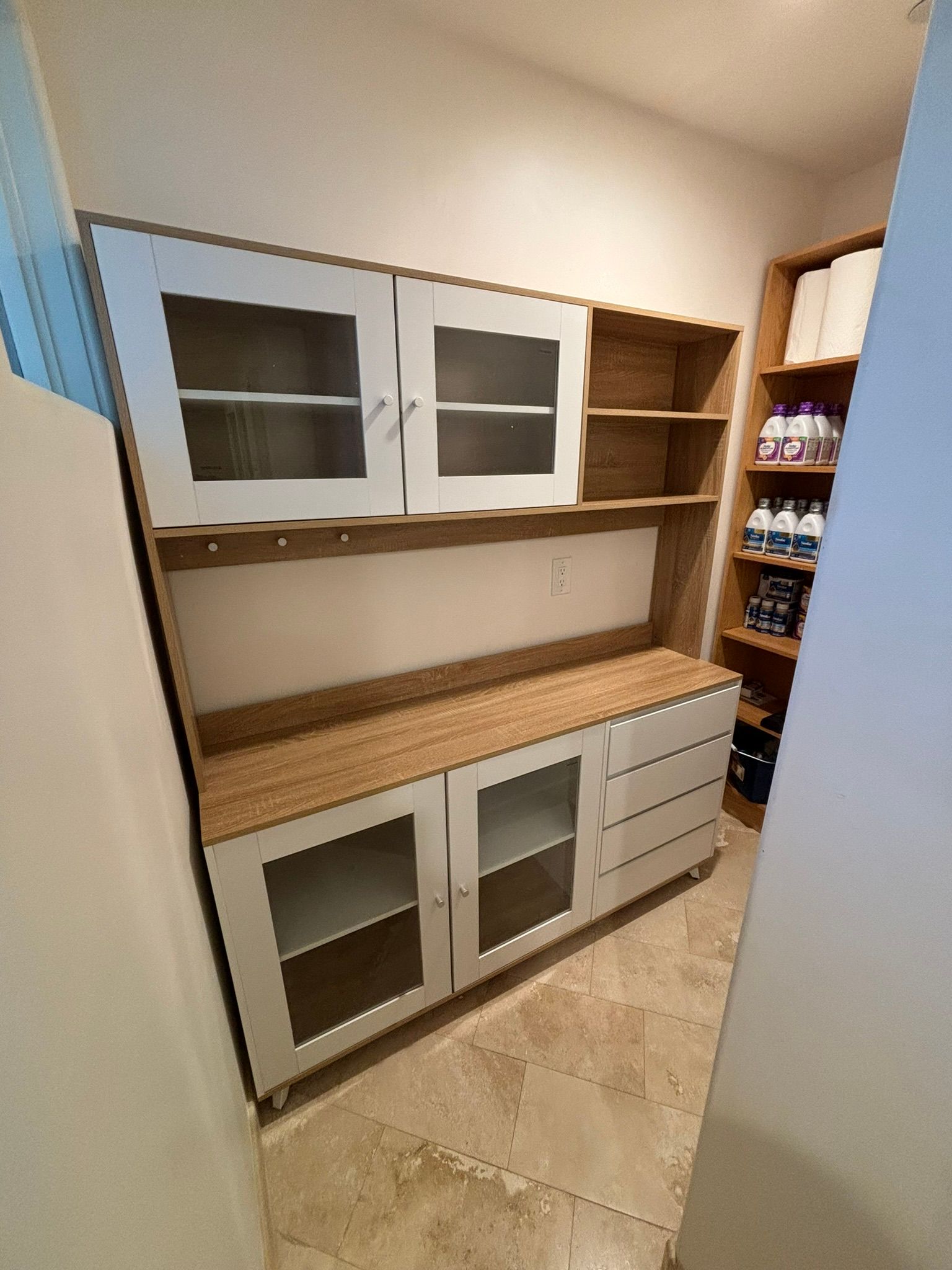 A pantry with white and wood cabinets. Glass door cabinets are on the bottom and top.