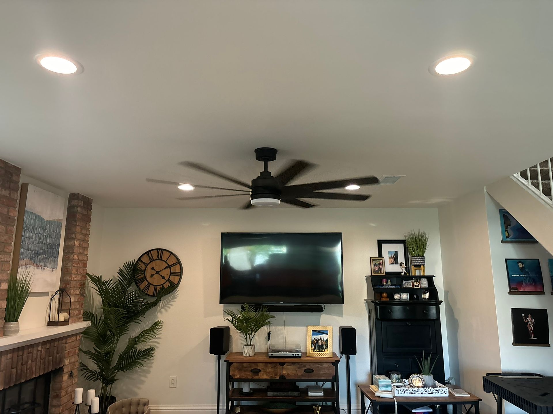 A living room with a flat screen tv and a ceiling fan