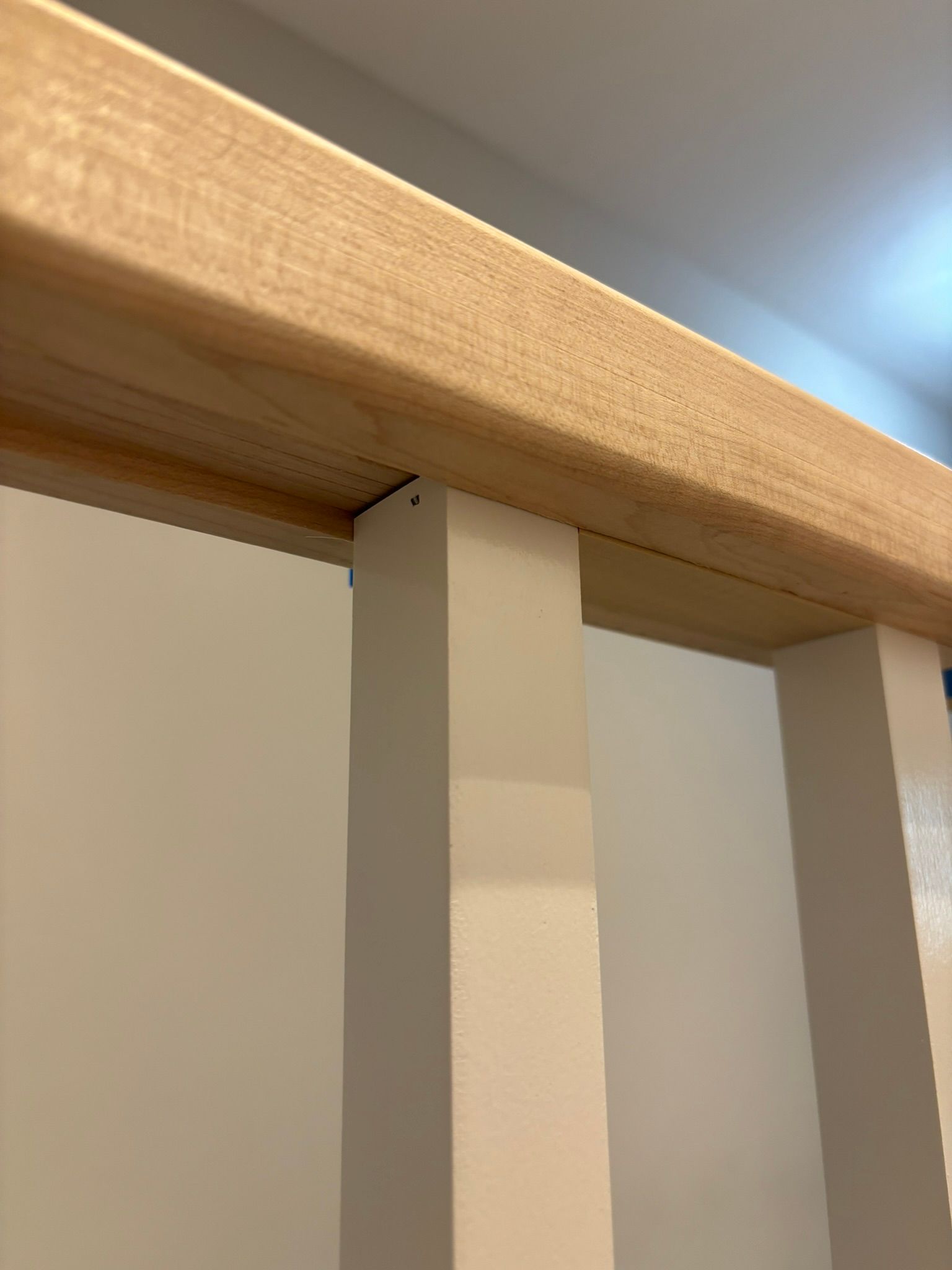 A close up of a wooden railing with white posts.