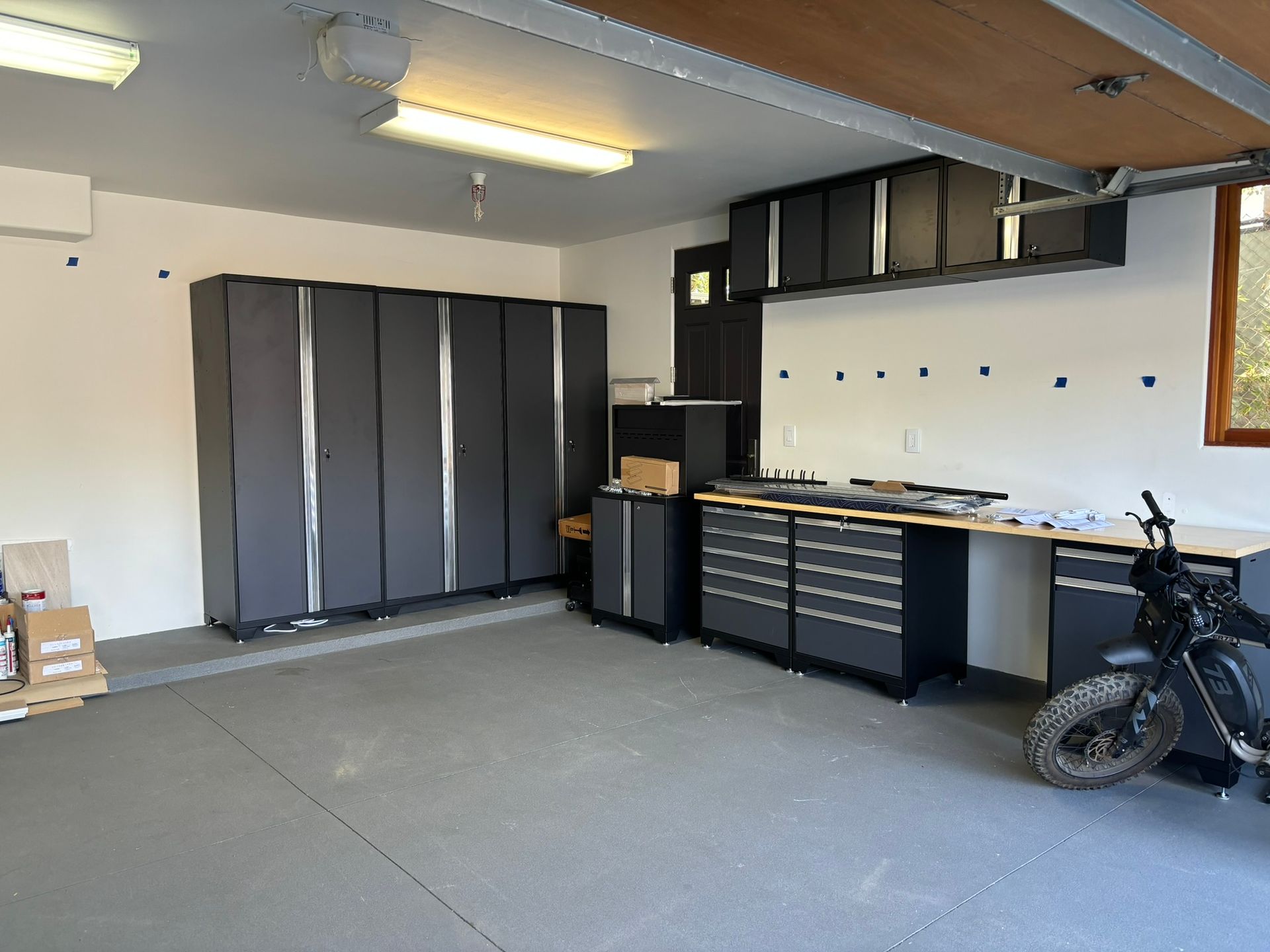 A motorcycle is parked in a garage with lots of cabinets.