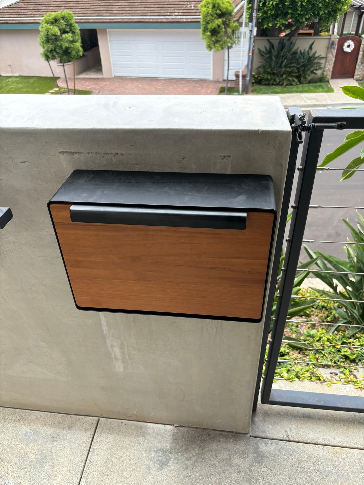 A wooden mailbox is attached to a concrete wall.