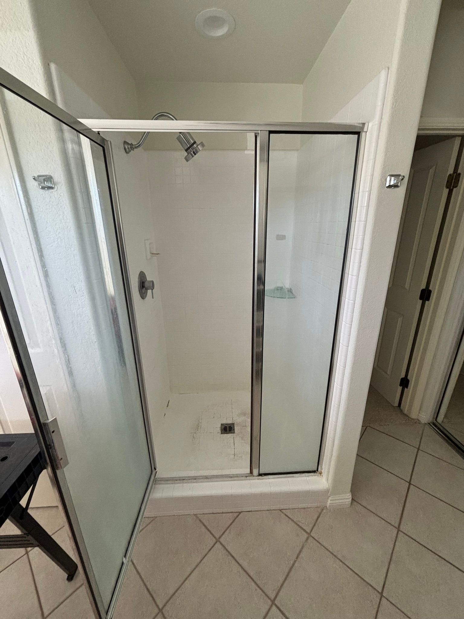 A bathroom with a shower stall with the door open.