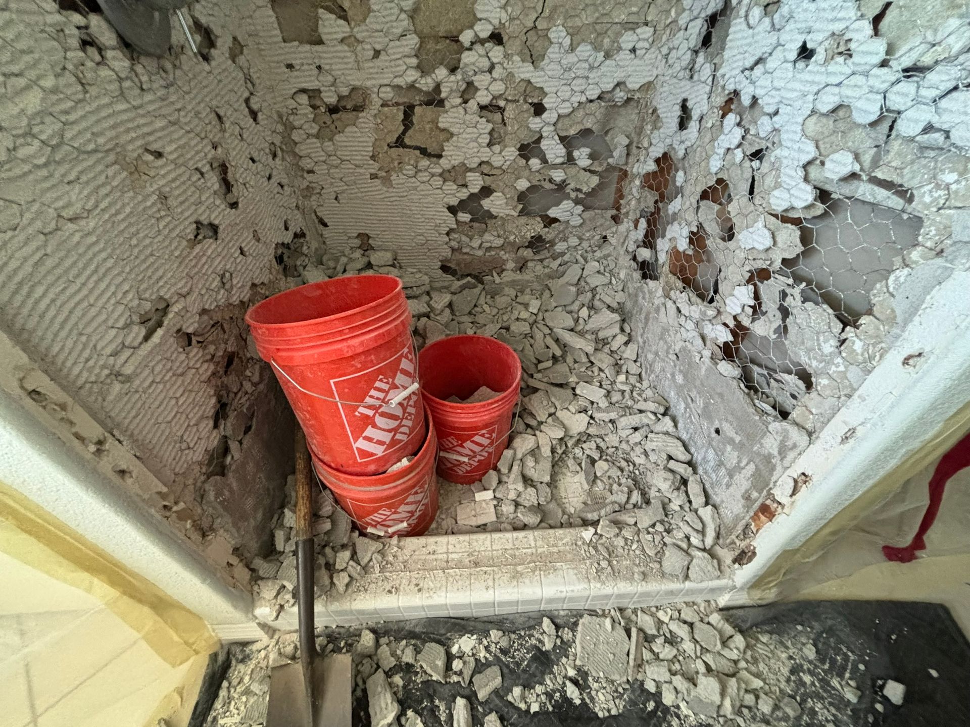 A demolition scene with rubble covering the floor. Red buckets are stacked inside the doorway.