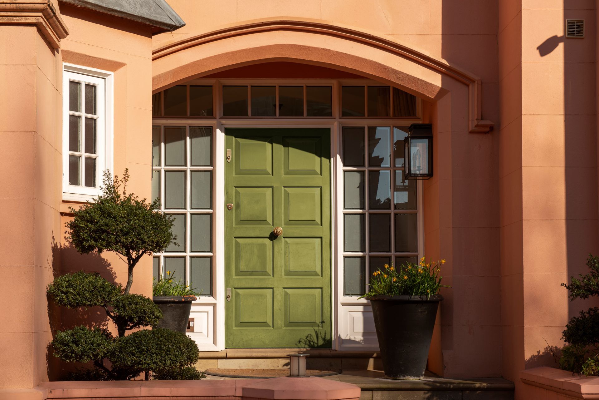 A house with a green door and potted plants in front of it