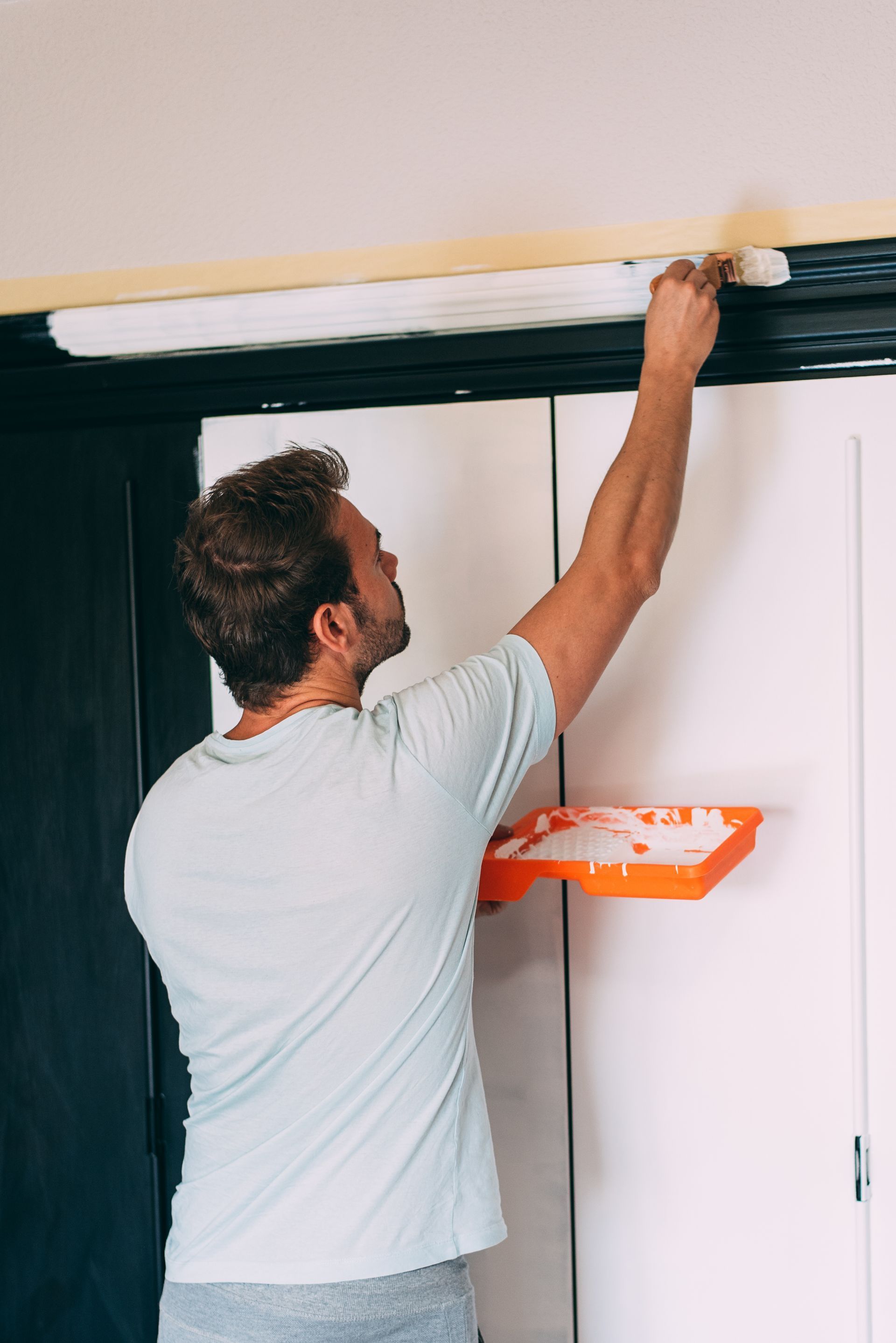 A man is painting a door with a brush.