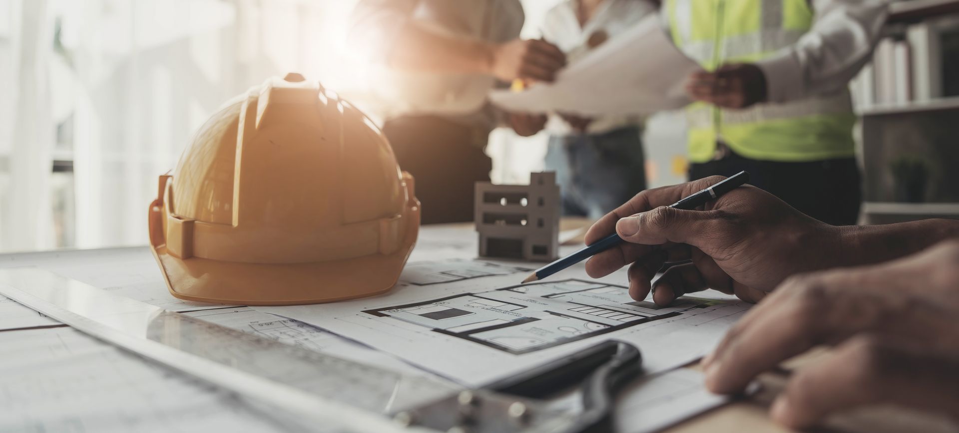 A group of construction workers are looking at a blueprint on a table.