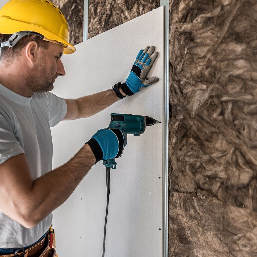 A man is using a drill on a wall.