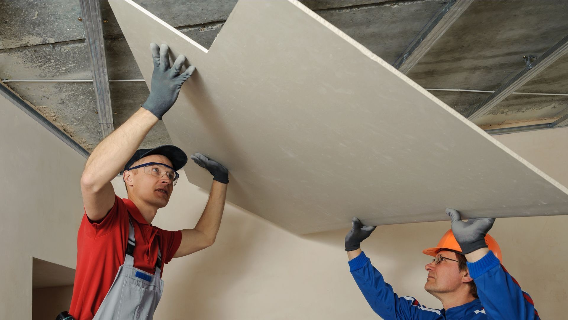 Two men are working on a ceiling in a room.