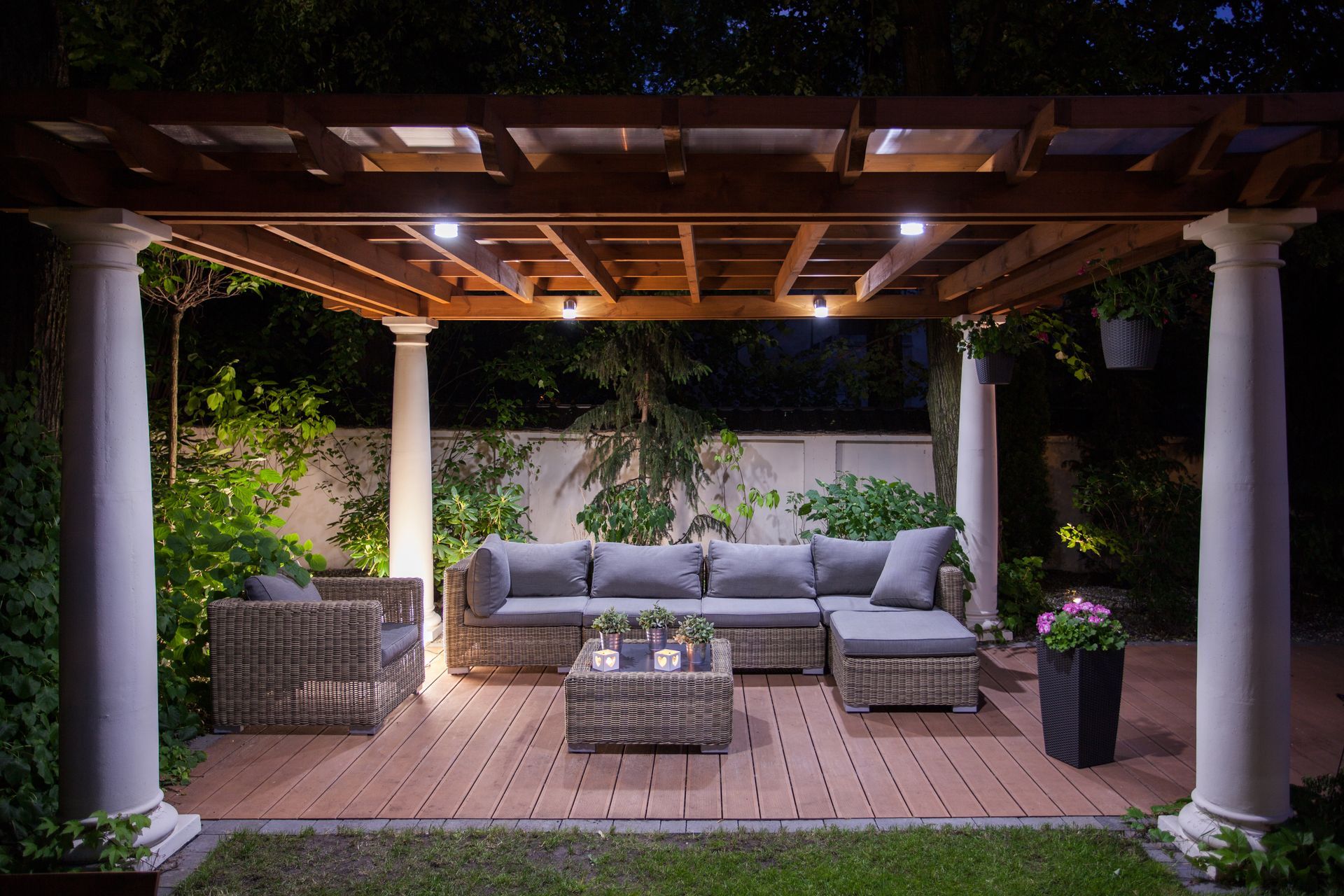 There is a pergola with a couch and chairs underneath it.