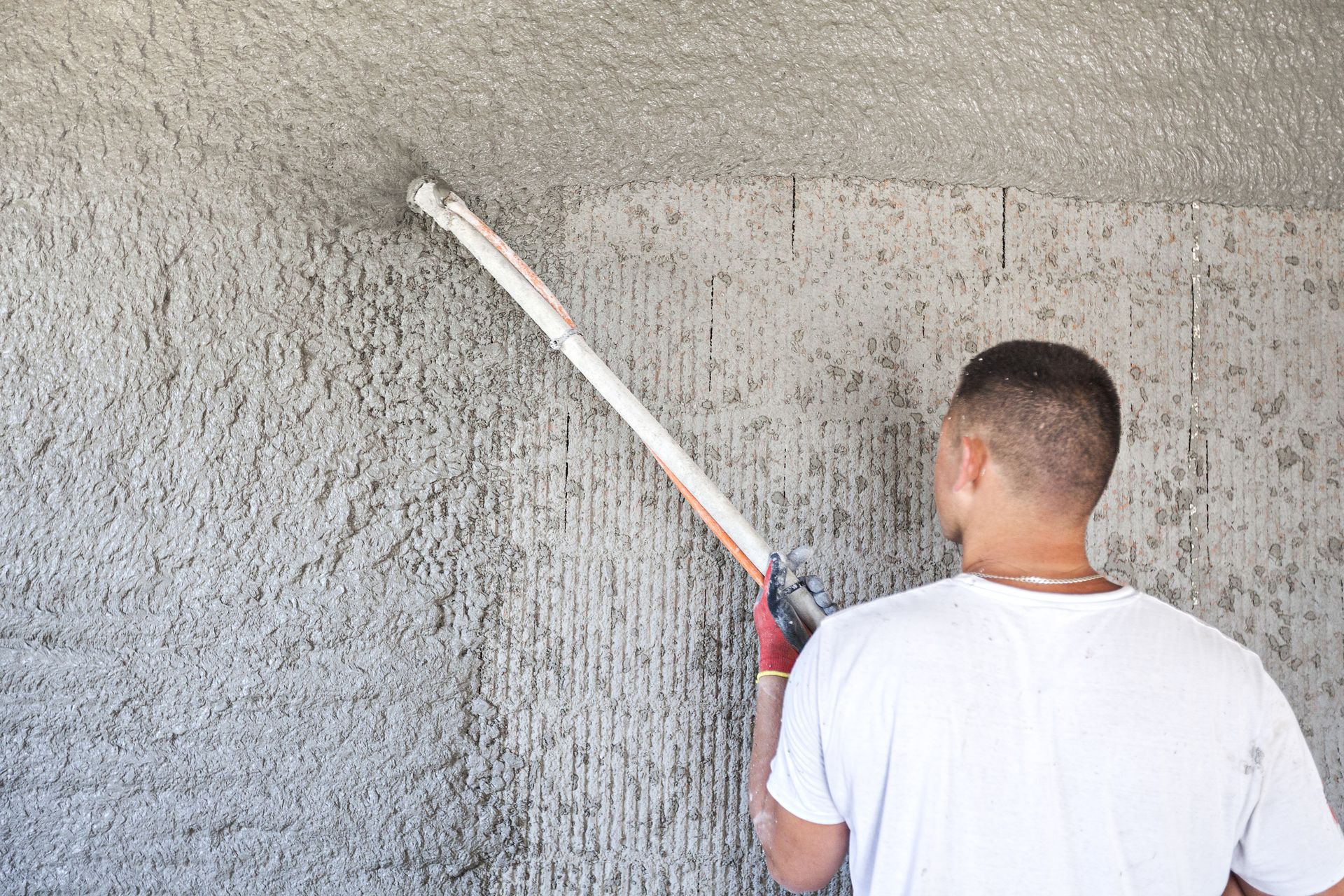 A man is painting a wall with a paint roller.