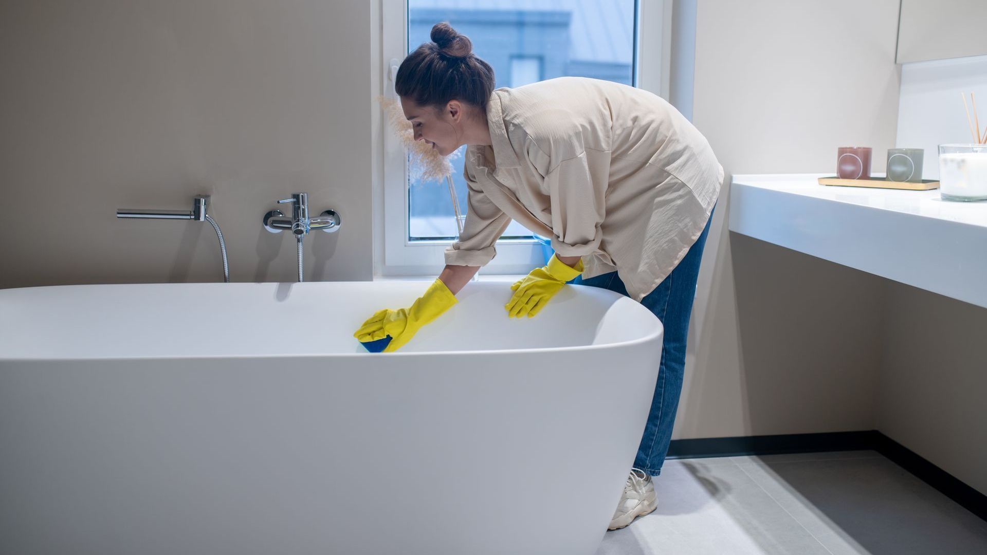 A woman is cleaning a bathtub in a bathroom.