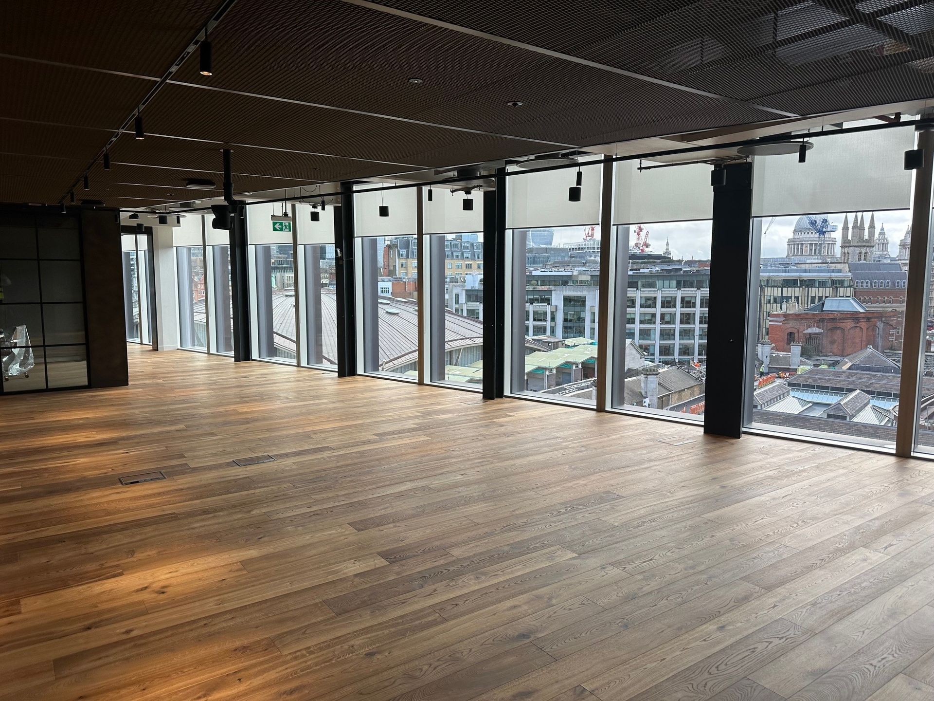 A large empty room with lots of windows and wooden floors.