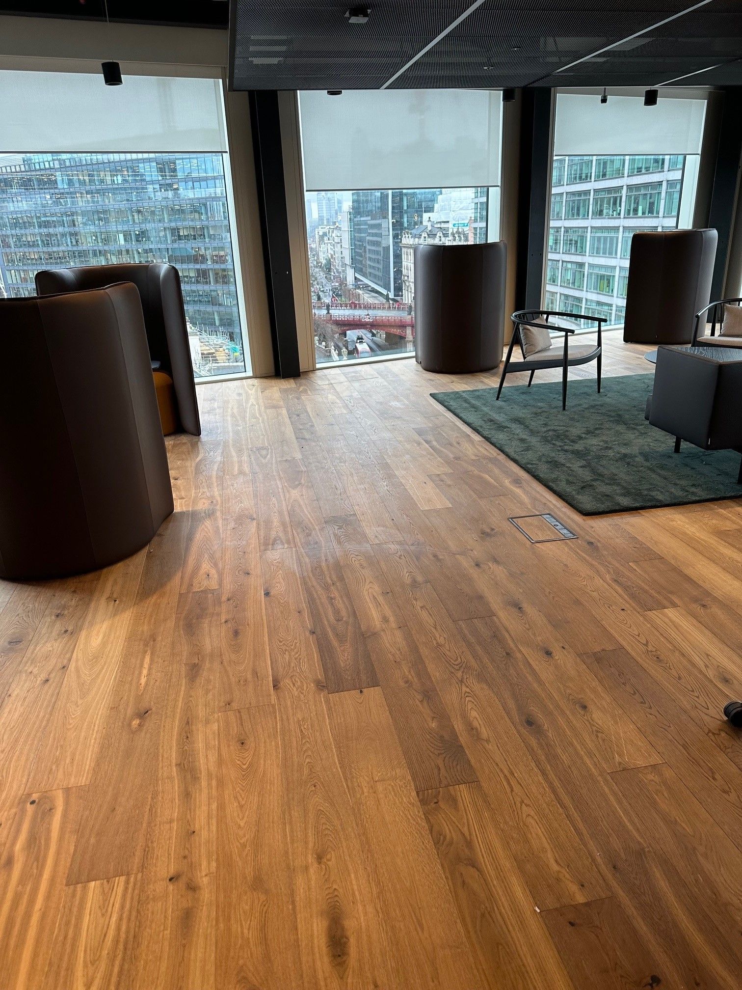 A living room with a wooden floor , chairs and a rug.