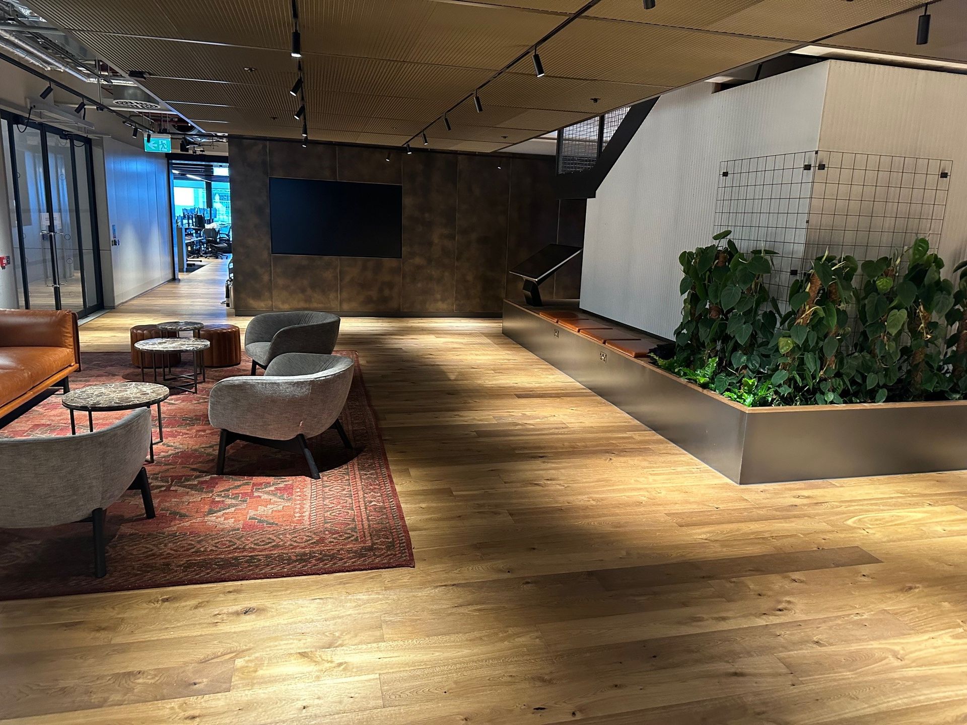 A living room with wooden floors , chairs , tables and a tv.