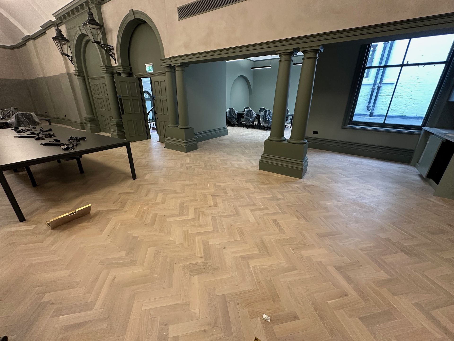 light wood parquet floorin a grand room with large windows ornate coving ,archways and pillars with a meeting table