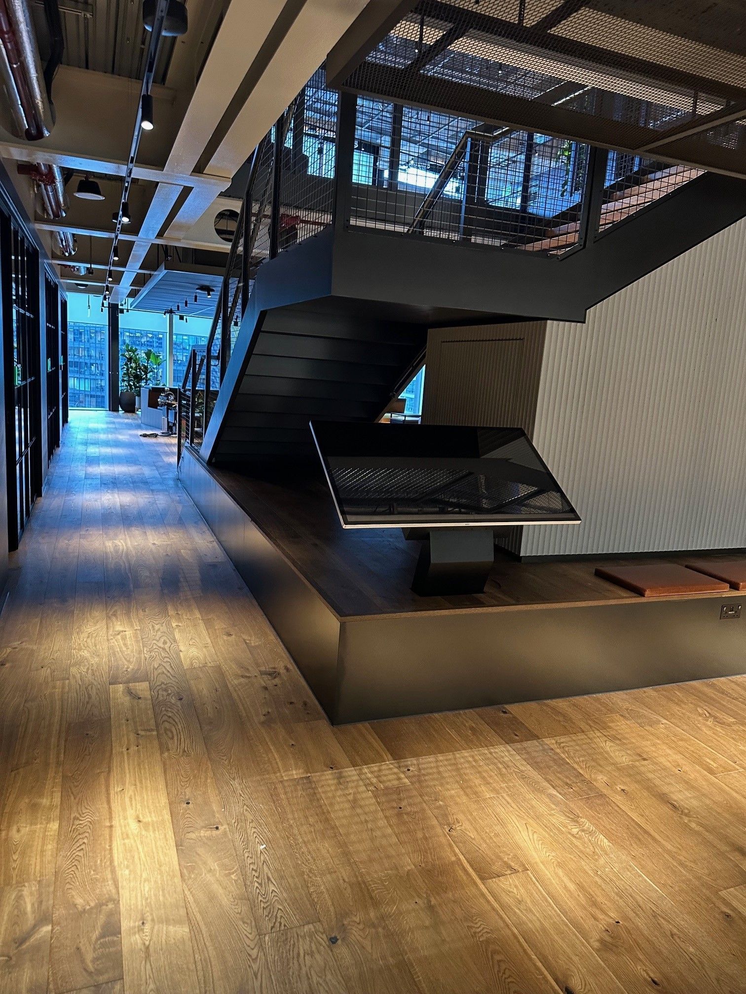 A hallway with wooden floors and stairs in a building