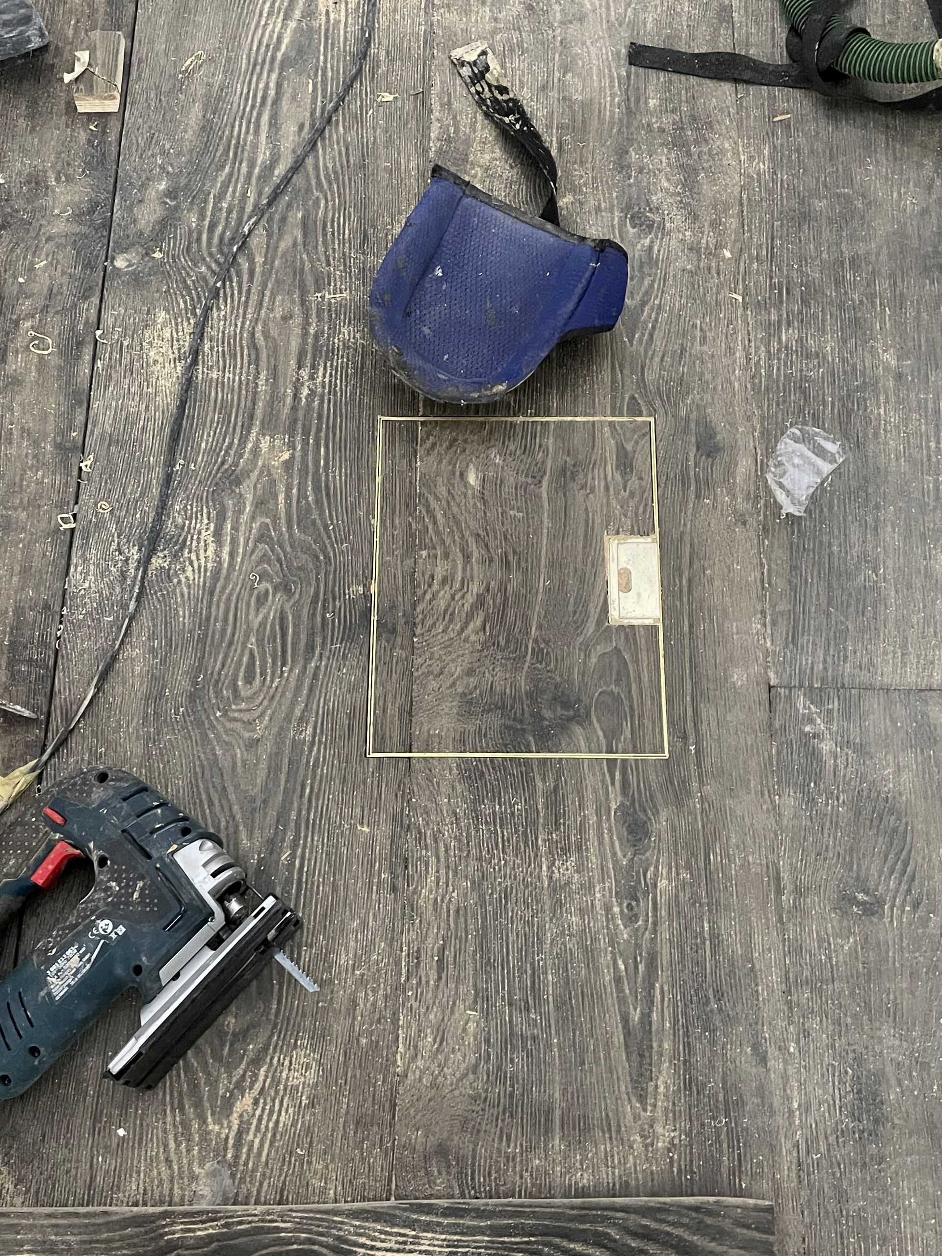 A wooden table with a drill and a tape measure on it.