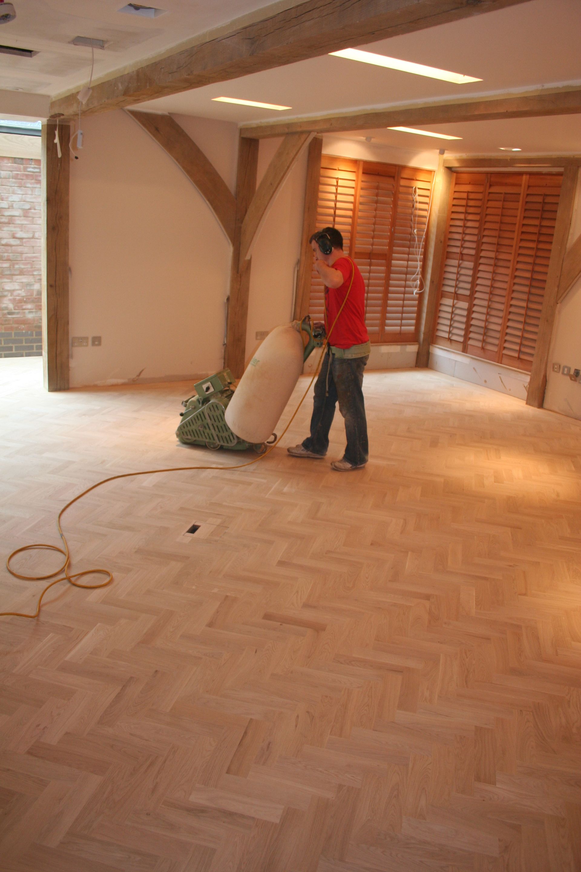 An employee of Dyfed Richards sanding a oak parquet floor