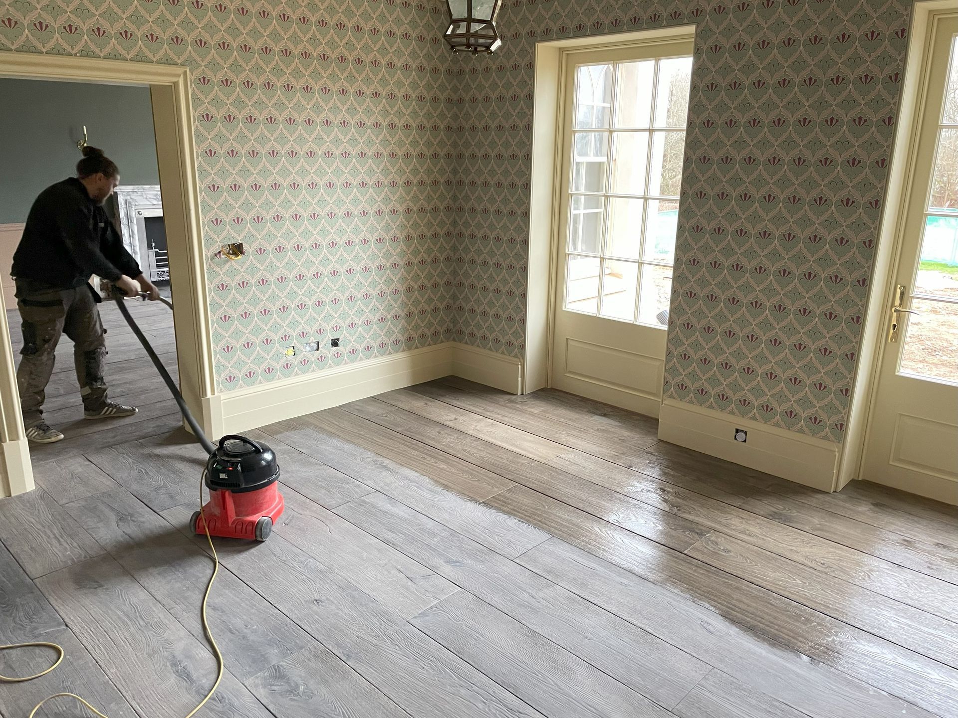 A man hoovering before he oils the wooden floor