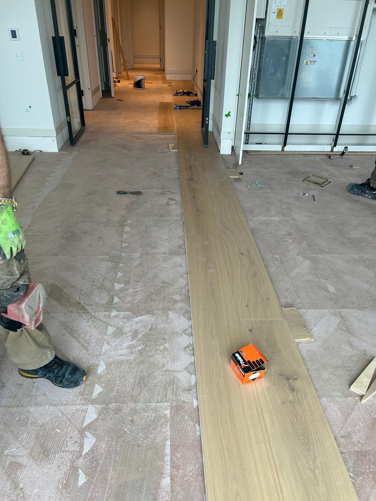 A person is standing next to a wooden floor in a hallway.