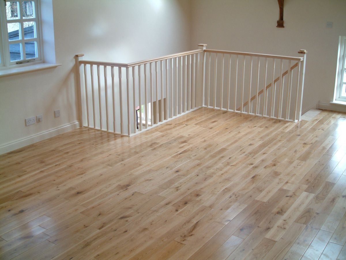 Interior with light wood floors, white railing, and staircase opening.