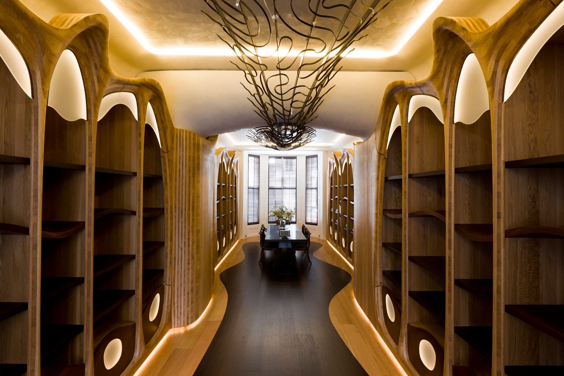 A long hallway with wooden shelves and a table in the middle