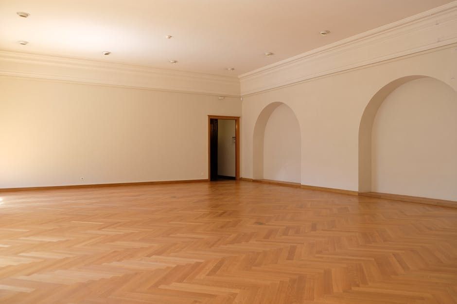 Empty room with wood floors and three arched alcoves.