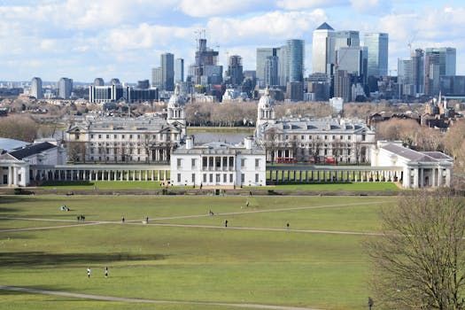 Greenwich park with historic buildings in the foreground, London skyline in the background, blue sky.
