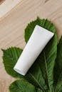 White cream tube on green leaves and wood background.