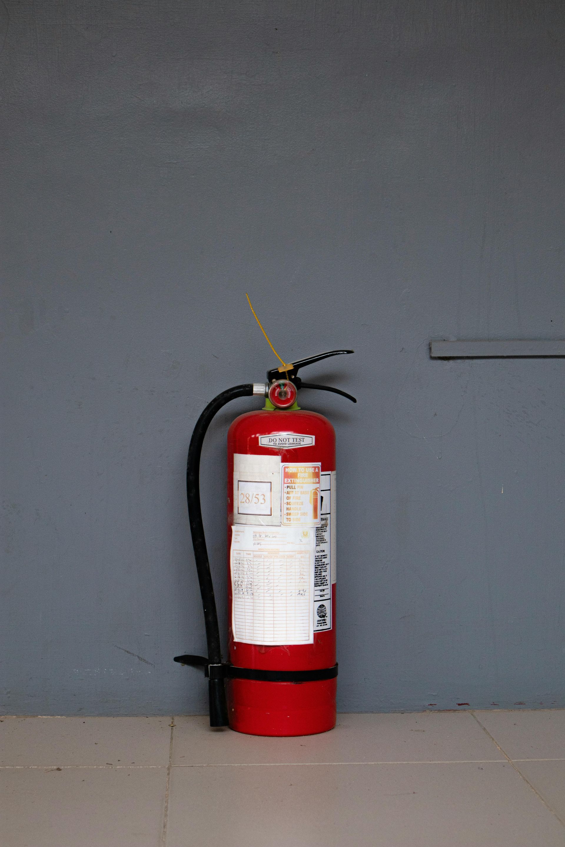 Red fire extinguisher against a gray wall.