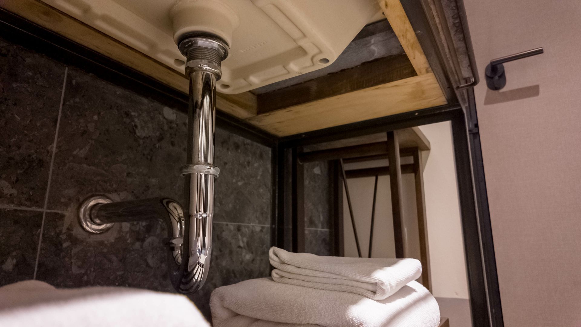 A bathroom sink with a stack of towels underneath it.