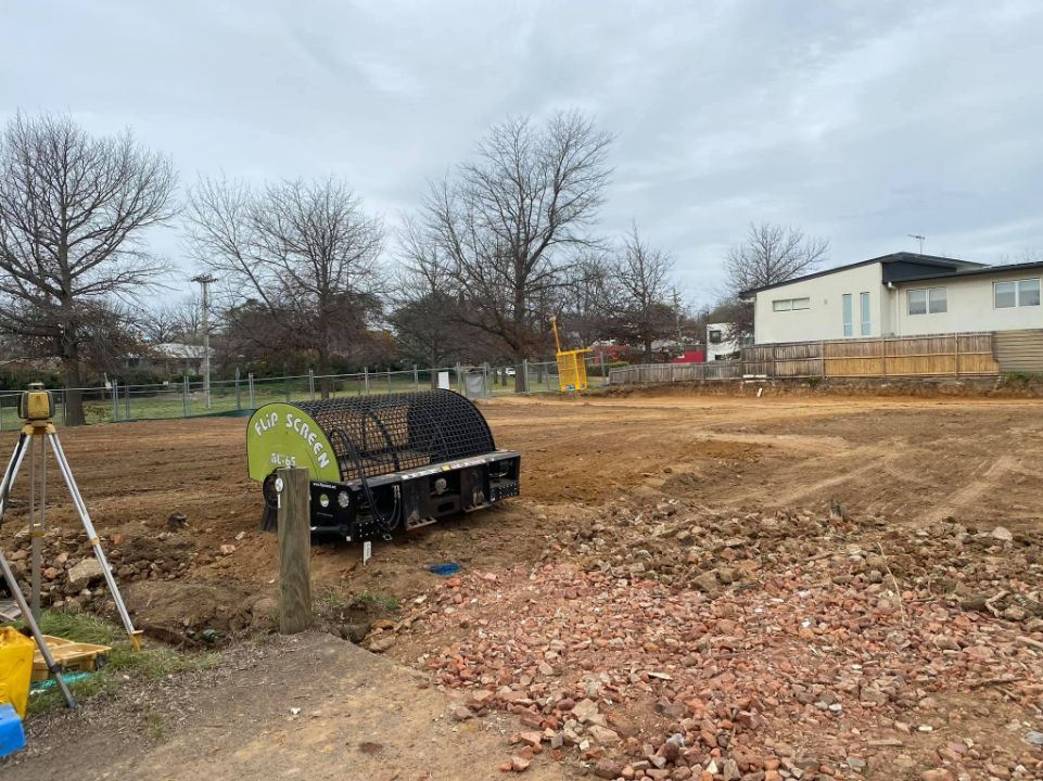 Construction Site, Ground Leveler Machine, Bare Trees, and a Building — Brucic Construction in Dickson, ACT