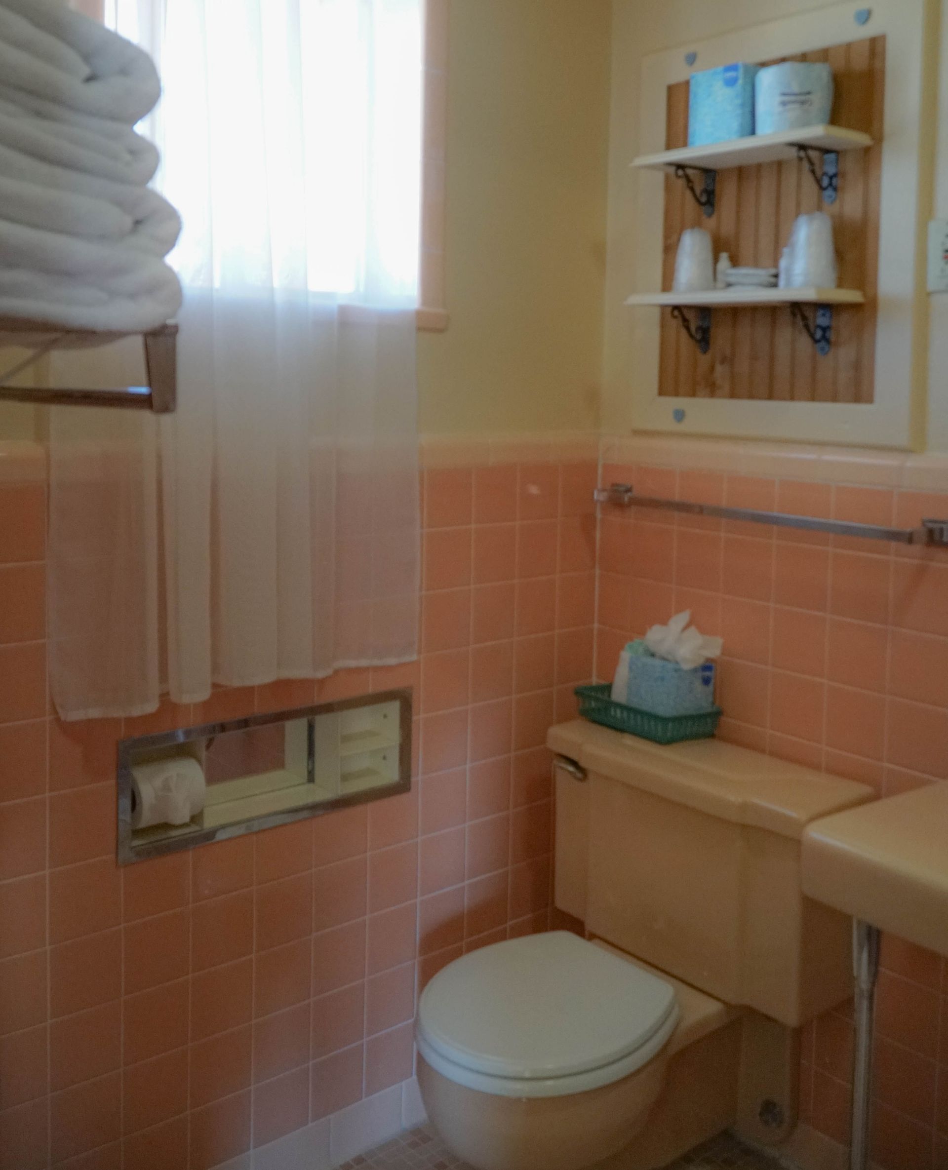 A bathroom with pink tiles and a toilet