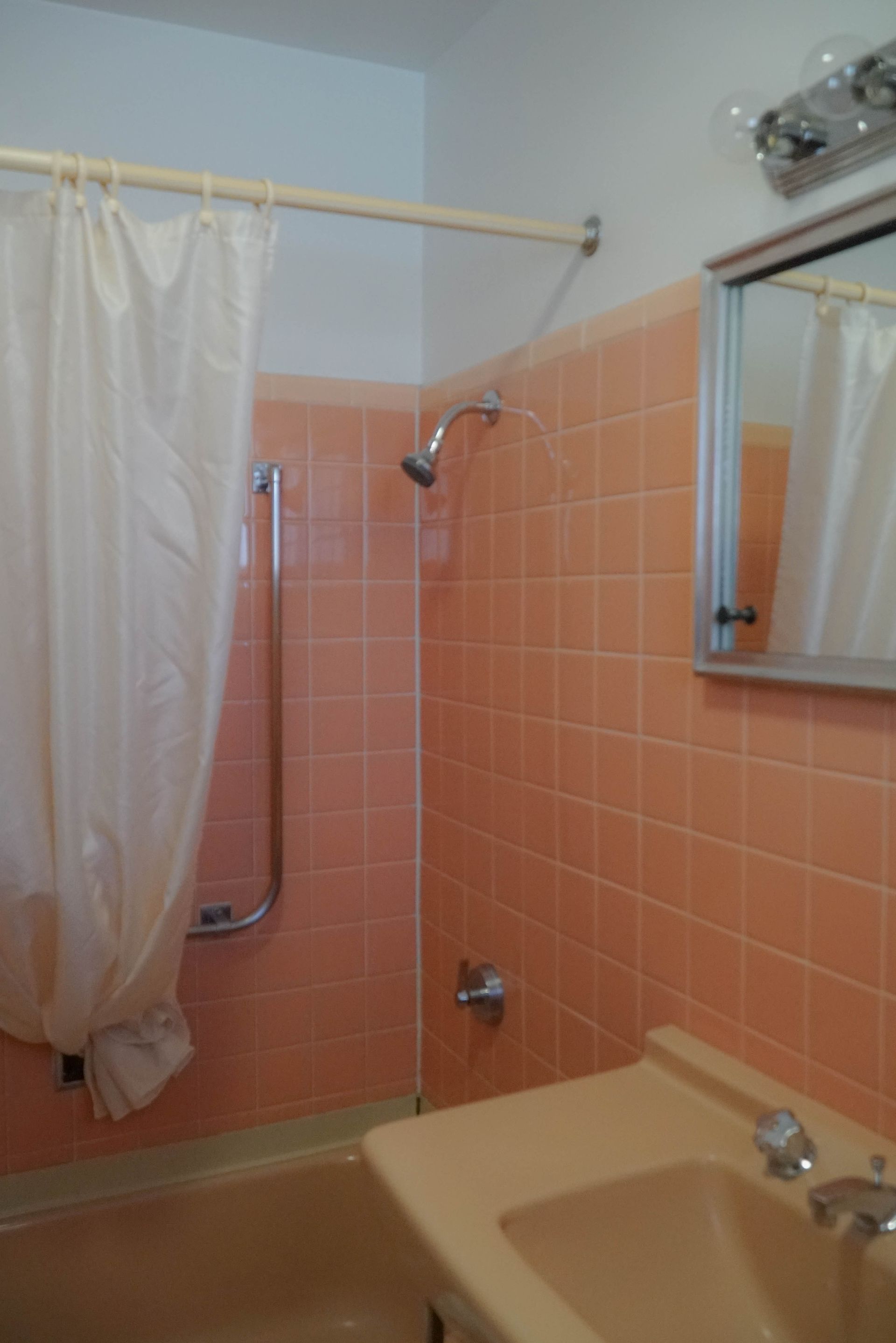 A bathroom with pink tiles and a sink and shower