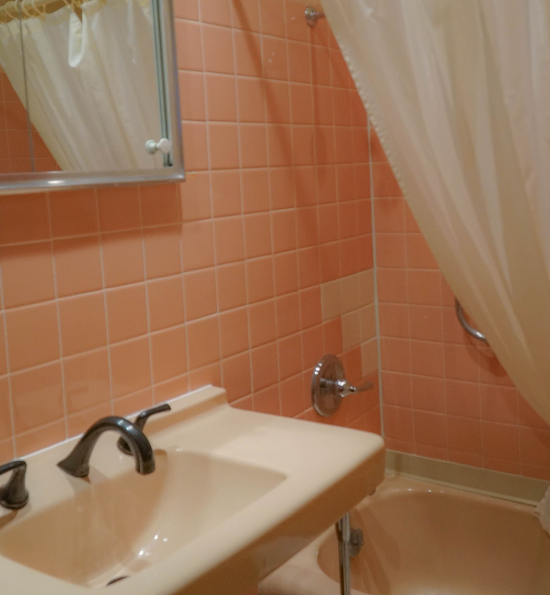 A bathroom with pink tiles and a sink and tub