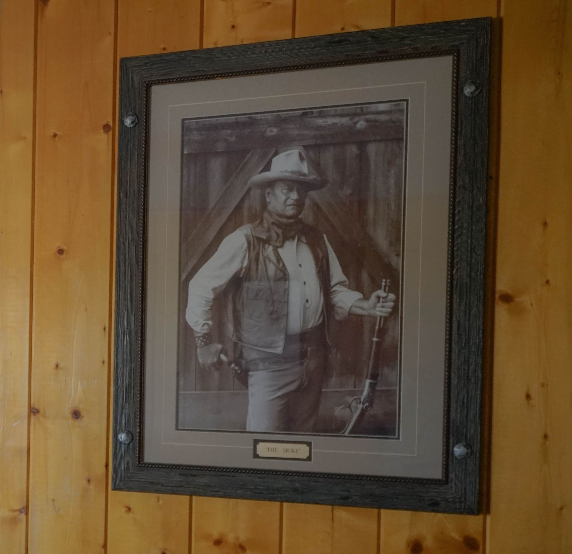 A picture of a man in a cowboy hat is framed on a wooden wall