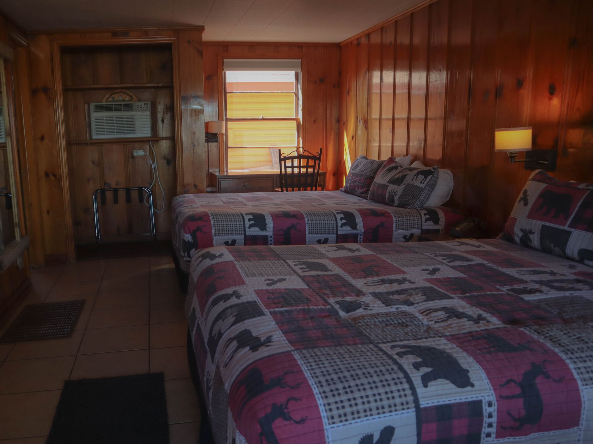 A hotel room with two beds and a window.