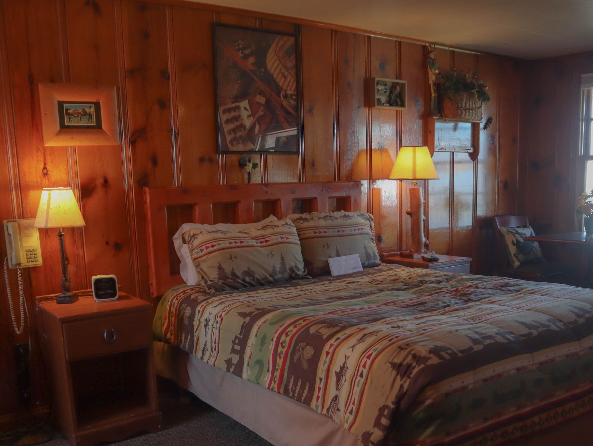 A bedroom with a bed , nightstand , lamps and a painting on the wall.