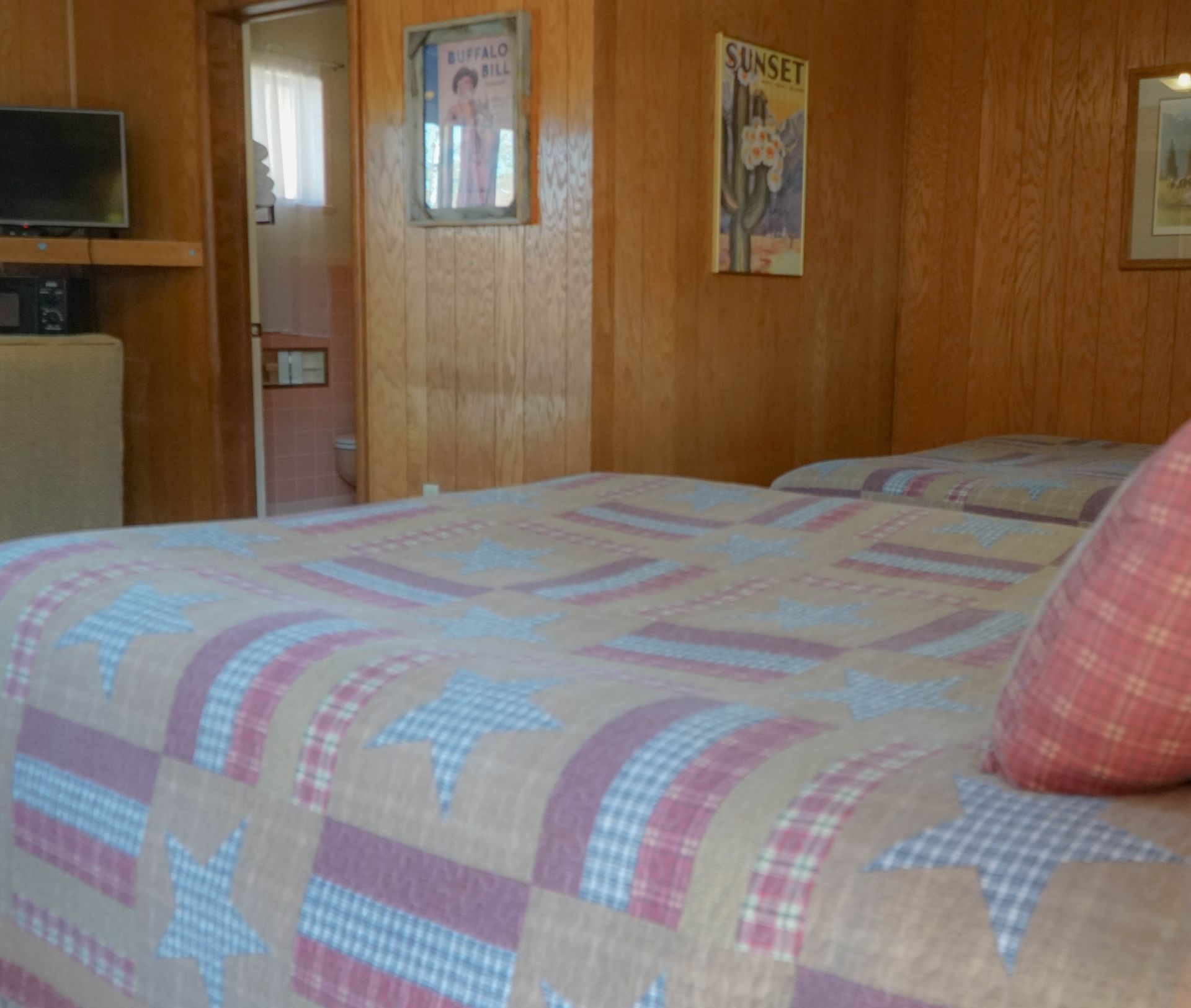 A bedroom with two beds and a sunset poster on the wall