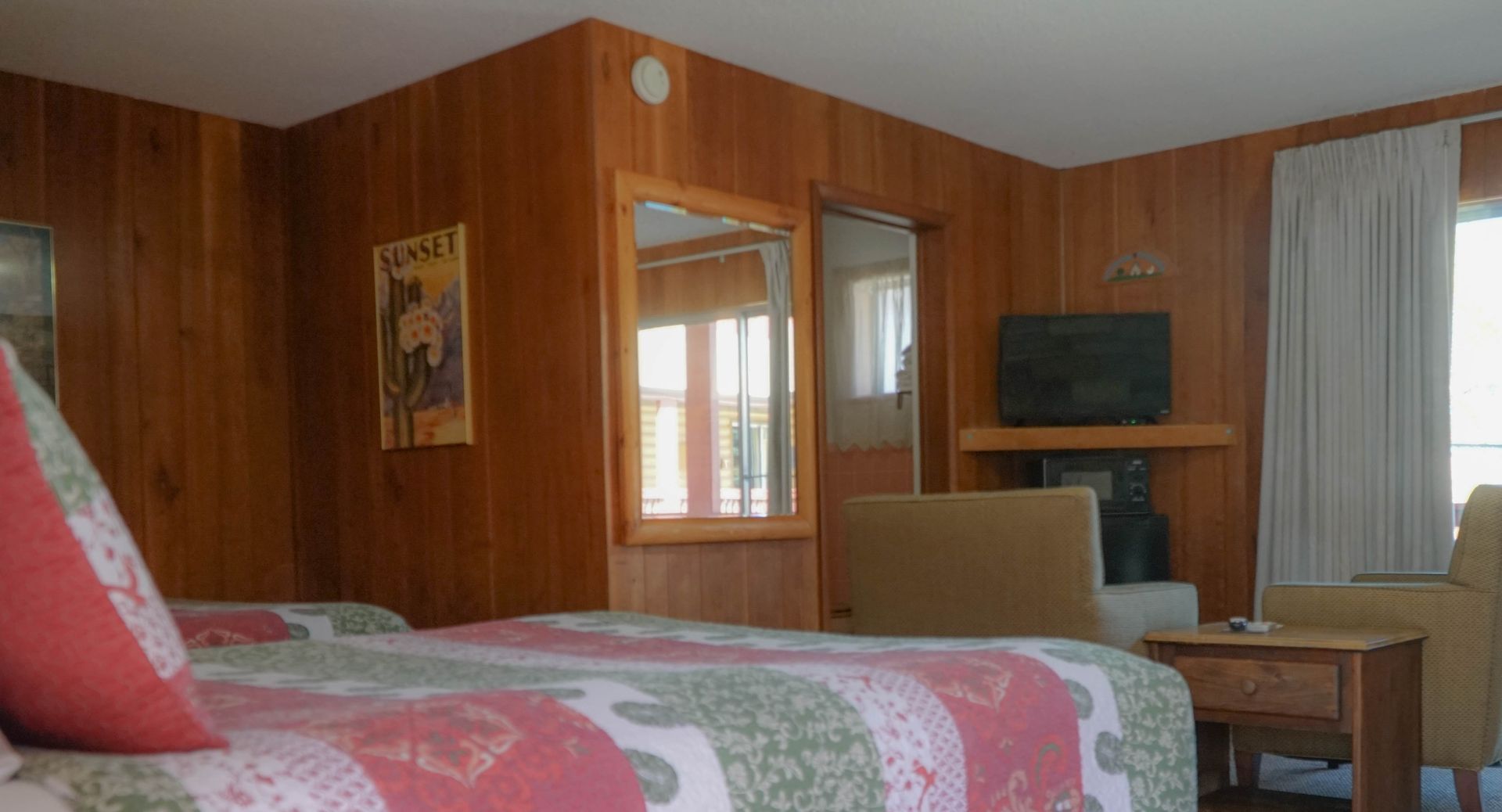 A hotel room with two beds , a television , a fireplace and a mirror.